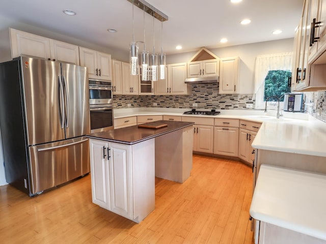 kitchen featuring light wood-type flooring, stainless steel appliances, sink, pendant lighting, and a center island