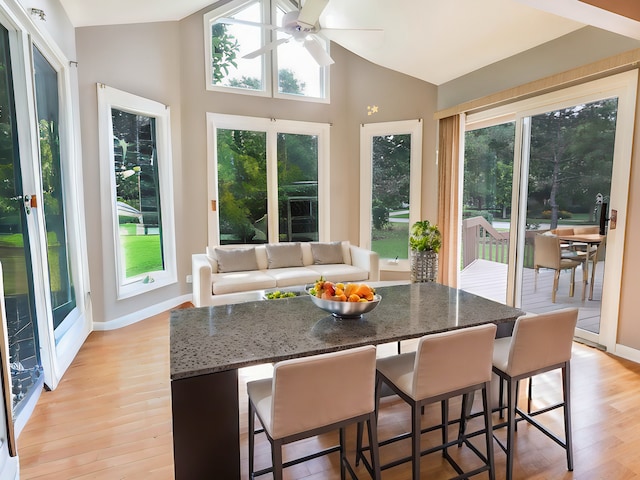 sunroom / solarium featuring ceiling fan, a healthy amount of sunlight, and lofted ceiling