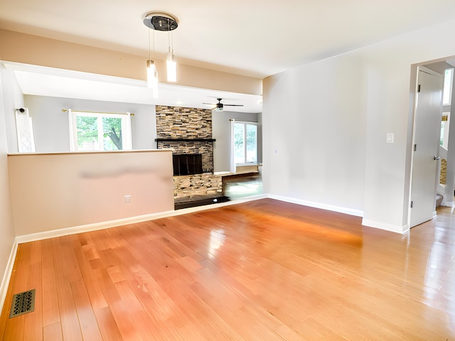 unfurnished living room with a fireplace, a wealth of natural light, hardwood / wood-style floors, and ceiling fan