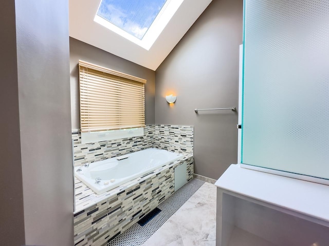 bathroom with lofted ceiling with skylight and tiled tub