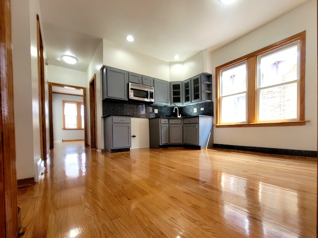 kitchen featuring sink, light hardwood / wood-style flooring, gray cabinetry, and tasteful backsplash