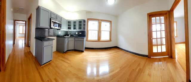 kitchen featuring decorative backsplash, a wealth of natural light, light wood-type flooring, and gray cabinets