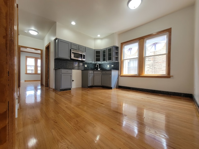 kitchen with backsplash, gray cabinetry, light hardwood / wood-style floors, and plenty of natural light