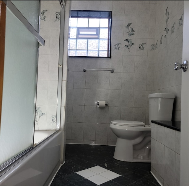 bathroom with toilet, enclosed tub / shower combo, tile walls, and tile patterned flooring