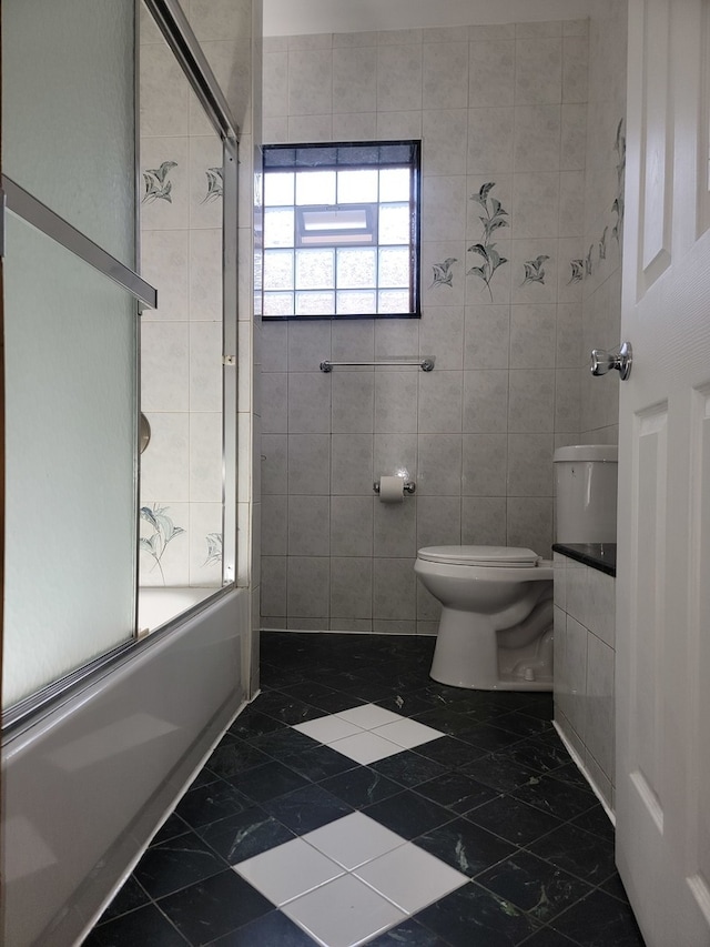 full bathroom with toilet, tile walls, vanity, and shower / bath combination with glass door