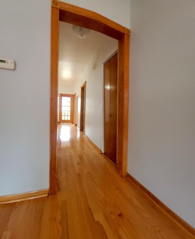 hall with light wood-type flooring and baseboards