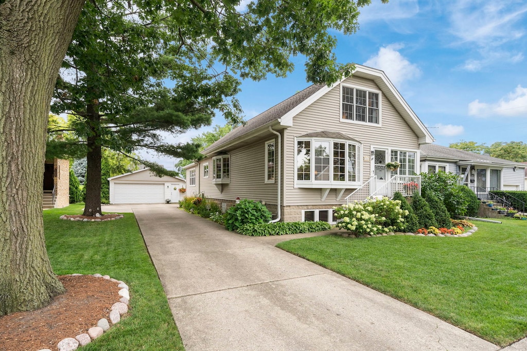 view of front facade with a garage, a front lawn, and an outbuilding