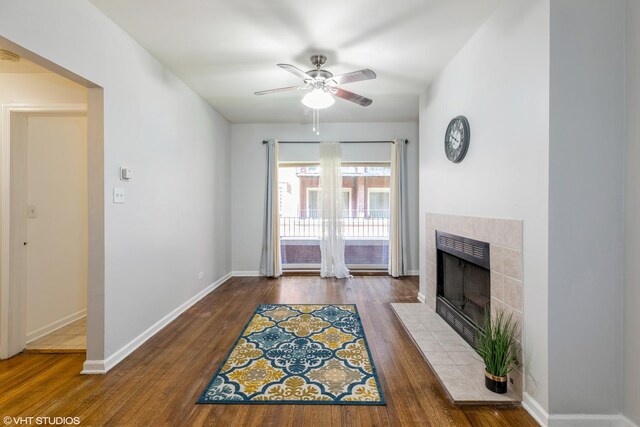 living room featuring dark wood-type flooring, a tile fireplace, and ceiling fan