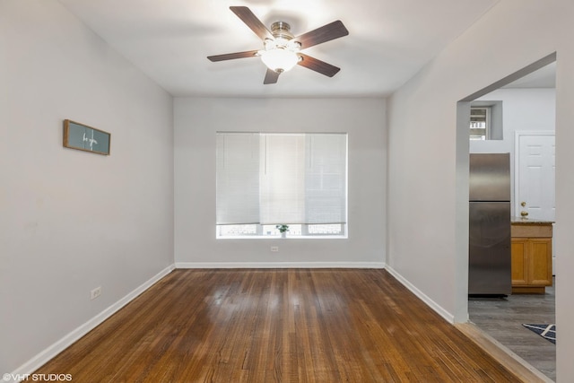 unfurnished room with dark wood-type flooring, ceiling fan, and baseboards