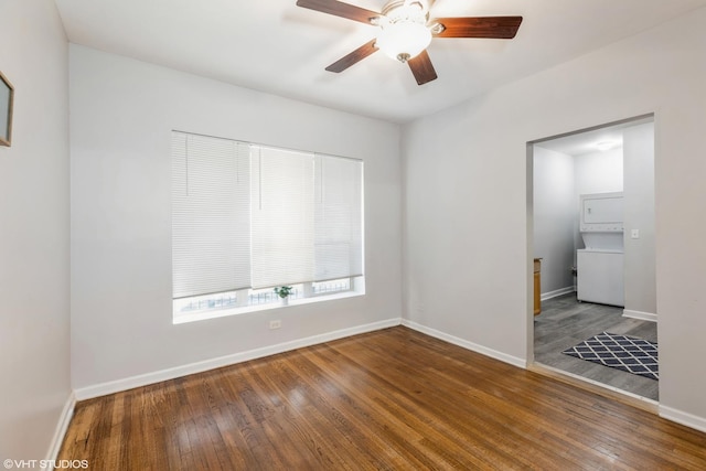 unfurnished room featuring stacked washing maching and dryer, ceiling fan, baseboards, and wood finished floors