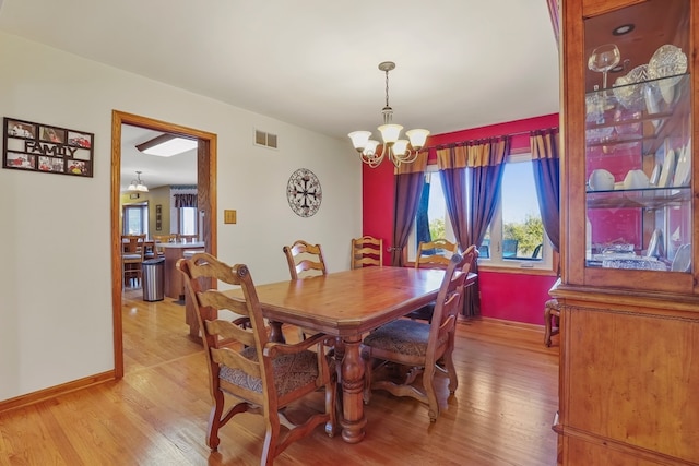 dining area with a healthy amount of sunlight, a notable chandelier, and light wood-type flooring