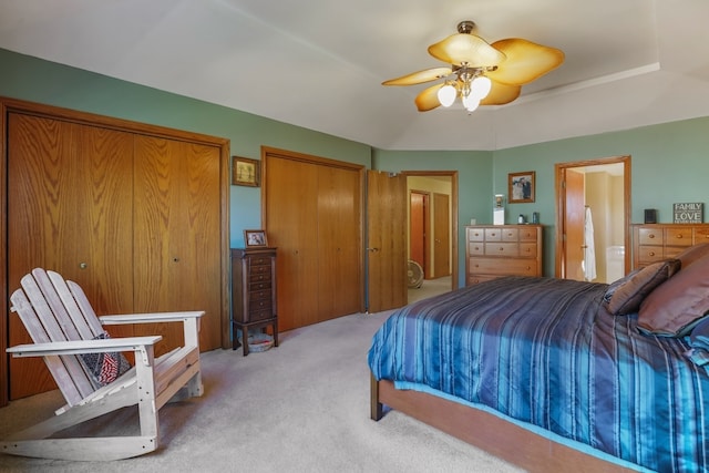 carpeted bedroom with ceiling fan and two closets