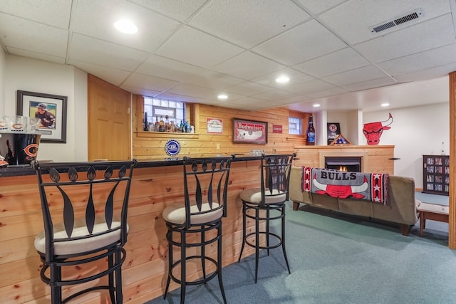 bar with a paneled ceiling, carpet, and wooden walls