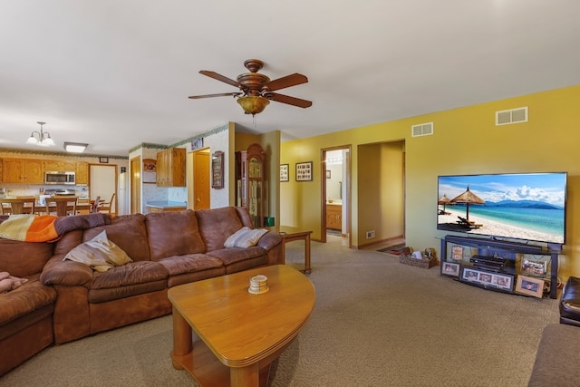 carpeted living room with ceiling fan with notable chandelier