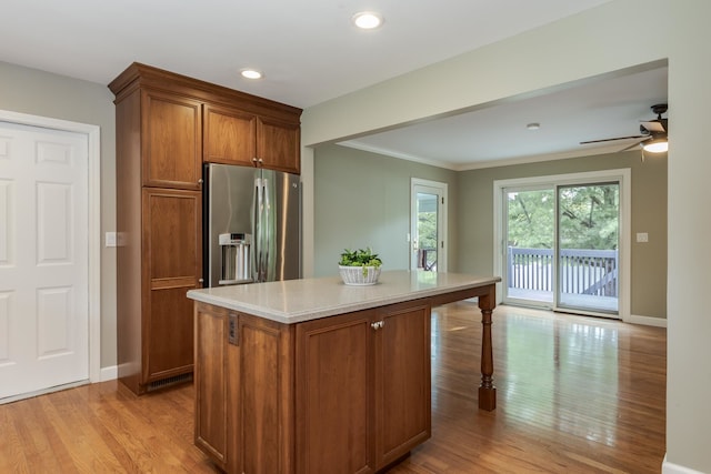 kitchen featuring ceiling fan, light stone countertops, a kitchen island, stainless steel fridge, and light hardwood / wood-style flooring