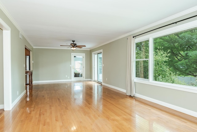 spare room featuring ceiling fan, ornamental molding, light hardwood / wood-style flooring, and a healthy amount of sunlight