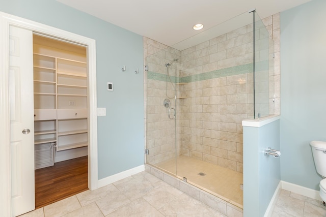 bathroom featuring tile patterned floors, toilet, and a shower with door