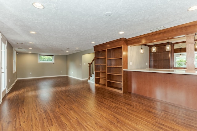 unfurnished living room with a wealth of natural light, a textured ceiling, and hardwood / wood-style floors