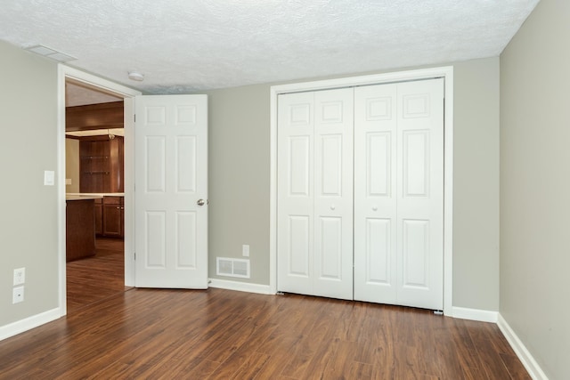 unfurnished bedroom with a closet, a textured ceiling, and hardwood / wood-style floors