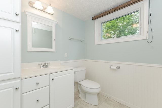 bathroom with vanity, a textured ceiling, toilet, and tile patterned flooring