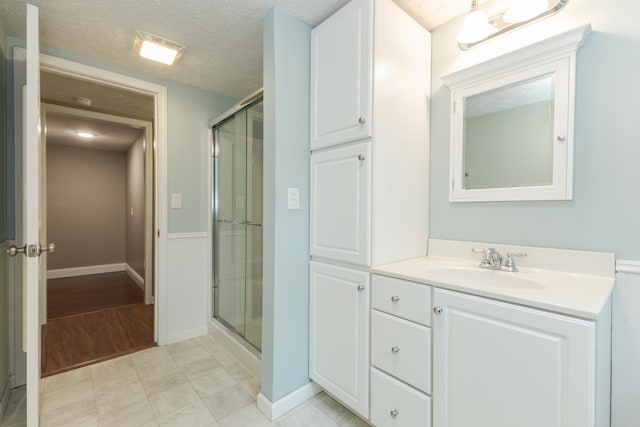 bathroom featuring hardwood / wood-style flooring, an enclosed shower, vanity, and a textured ceiling