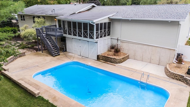 view of swimming pool featuring a patio, a sunroom, and a wooden deck