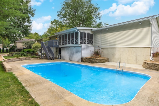 view of swimming pool featuring a deck, a patio, and a sunroom