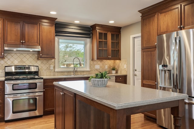 kitchen with light hardwood / wood-style floors, appliances with stainless steel finishes, backsplash, and sink