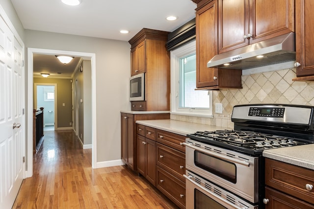 kitchen featuring double oven range, backsplash, and light hardwood / wood-style floors