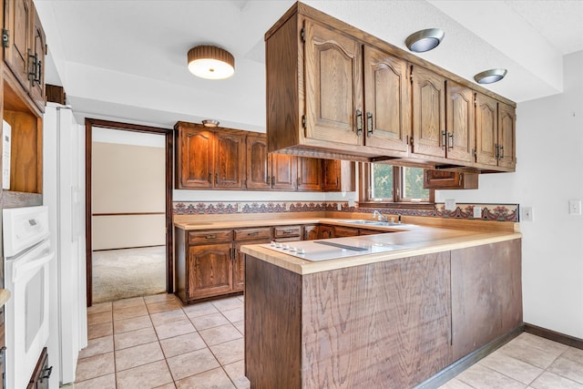 kitchen with oven, sink, kitchen peninsula, and light tile patterned floors