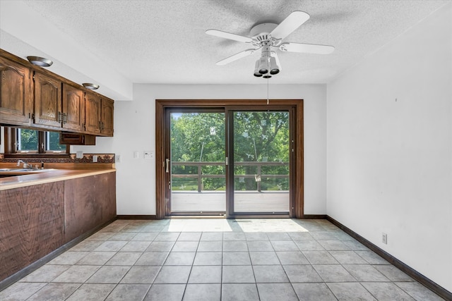 kitchen featuring light tile patterned flooring, a textured ceiling, sink, and ceiling fan