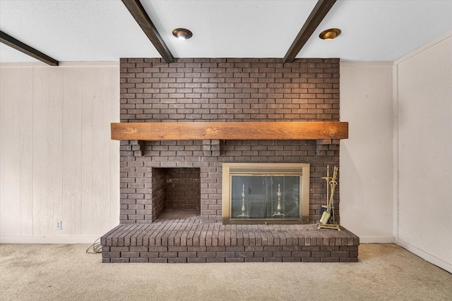 interior details featuring a fireplace, beamed ceiling, and carpet flooring