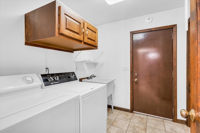 washroom featuring light tile patterned flooring, washer and dryer, and cabinets