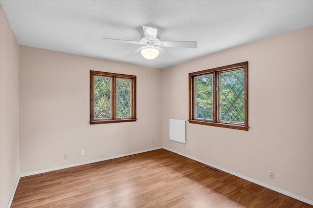 empty room featuring light hardwood / wood-style flooring, a textured ceiling, and ceiling fan