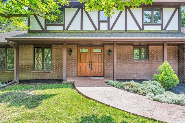 tudor-style house featuring a porch and a front lawn