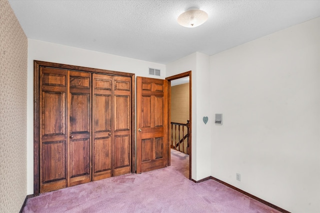 bedroom featuring light colored carpet, a closet, and a textured ceiling