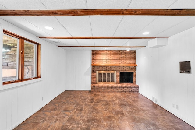 unfurnished living room featuring brick wall, a paneled ceiling, tile patterned flooring, and a brick fireplace