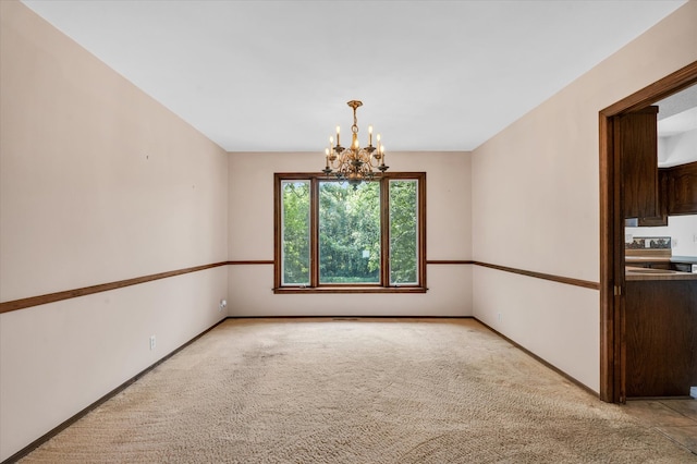 spare room featuring a chandelier and light carpet