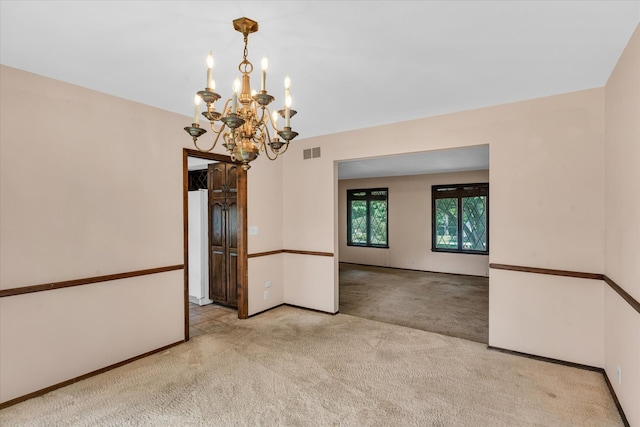 spare room with light carpet and a chandelier