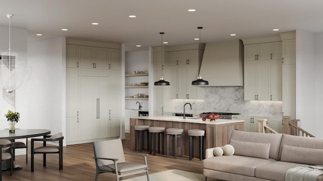 kitchen with wall chimney exhaust hood, a center island with sink, pendant lighting, and a kitchen bar