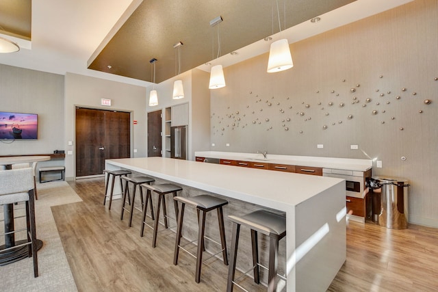 kitchen featuring a center island, high end fridge, light hardwood / wood-style floors, and decorative light fixtures