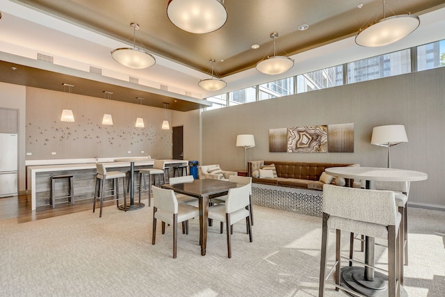 carpeted dining area with a tray ceiling, a wealth of natural light, and a high ceiling