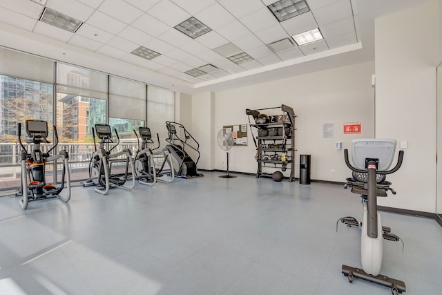 exercise room with a paneled ceiling and expansive windows