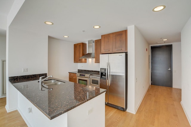 kitchen featuring wall chimney exhaust hood, stainless steel appliances, kitchen peninsula, and sink