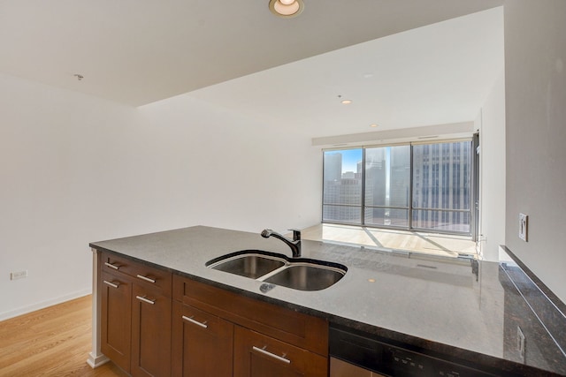 kitchen featuring dishwasher, sink, dark stone countertops, and light hardwood / wood-style floors