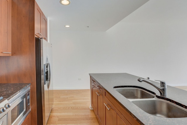 kitchen with stainless steel appliances, sink, and light hardwood / wood-style flooring