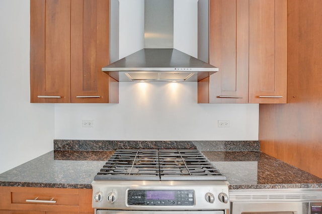 kitchen with wall chimney range hood, gas stove, and dark stone counters