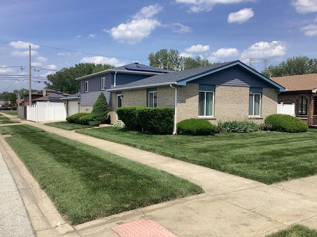 view of front of property with a garage, brick siding, fence, and a front yard