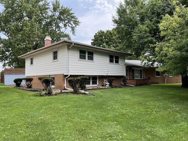 rear view of house featuring brick siding, a chimney, and a yard