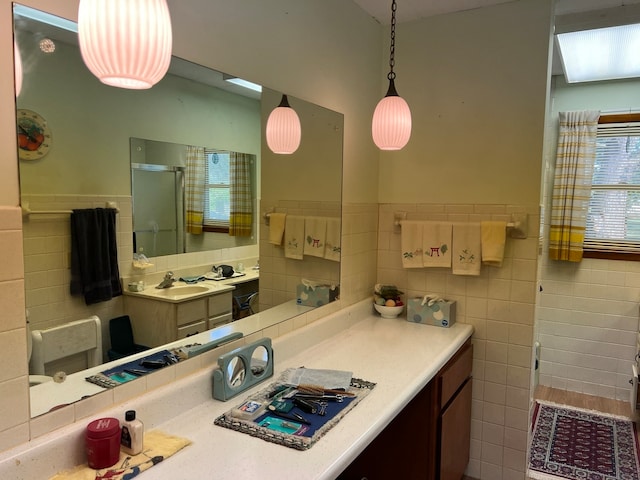 bathroom with tile walls, a shower with door, and vanity